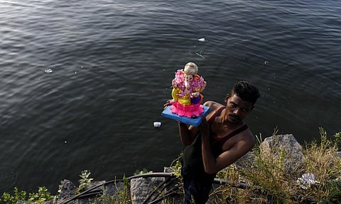 A devotee is about to immerse an idol of Ganesha in Hussainsagar. (Photo | Vinay Madapu, EPS)