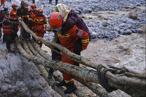 Rescuers carry a villager across a river following an earthquake in Moxi Town of Luding County, Sichuan Province on Monday. (Photo | AP)