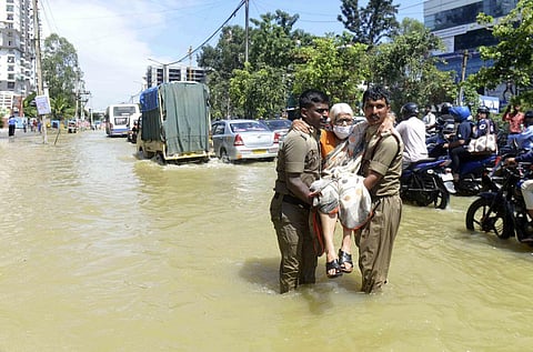 Firefighters help an elderly woman move to a safer area after heavy rainfall in Bangalore, India, Monday, Sept. 5, 2022. (Photo | AP)