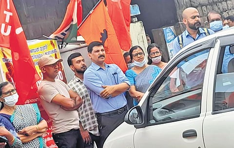 Employees of the Hindustan Insecticides Ltd block the vehicle of unit head Pramod Sankpal in front of the factory gate at Udyogamandal in Kochi on Monday