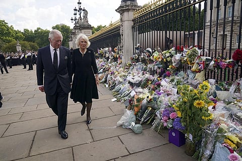 Britain's King Charles III and Camilla, the Queen Consort, walk past floral tributes left outside Buckingham Palace following death of Queen Elizabeth II, in London on Friday. (Photo | PTI)