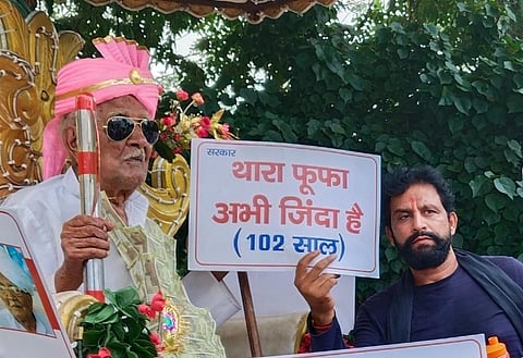 Duli Chand with the Your uncle (Fufa) is alive (102 years)' placard. (Photo | Special Arrangement)