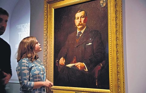 A Museum of London employee poses for photographers next to an 1897 oil on canvas portrait of Sherlock Holmes author Sir Arthur Conan Doyle. (Photo | AP)