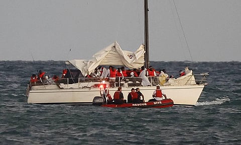 U.S. Coast Guard members pull up alongside a sailboat carrying a large group of migrants off Virginia Key near Key Biscayne. (Photo | AP)