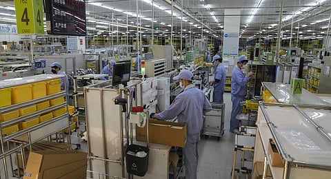 Workers assembly machinery parts at SMC China, a Japanese joint venture pneumatic engineering company factory in Beijing. (Photo | AP)