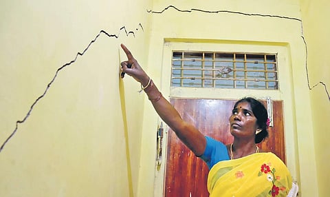 Representational image of a woman showing cracks on the wall of her house. (Photo | EPS, S Dinesh)