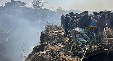 Rescuers and onlookers gather at the site of a plane crash in Pokhara. (Photo | AFP)