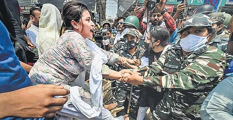 A woman is taken away by security personnel while trying to stop a bulldozer during a protest againt the encroachment drive conducted by the South Delhi Municipal Corporation at Shaheen Bagh in May