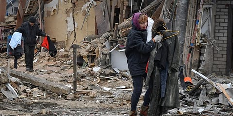 Local residents carry their belongings as they leave their home ruined in the Saturday Russian rocket attack in Zaporizhzhya, Ukraine on January 1. (Photo | AP)