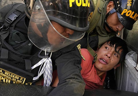 Anti-government protesters who traveled to the capital to march against Peruvian President Dina Boluarte, is detained and thrown on the back of police vehicle during clashes. (Photo | AP)