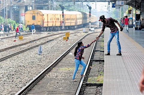 A man helps his friend to get onto platform 1 of Ernakulam Town railway station since the foot overbridge is undergoing maintenance | A Sanesh
