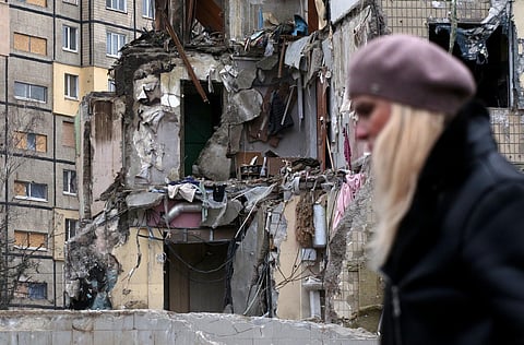 A woman walks past a residential building in the Ukrainian city of Dnipro on January 22, 2023, destroyed as a result of a missile strike. (Photo | AFP)