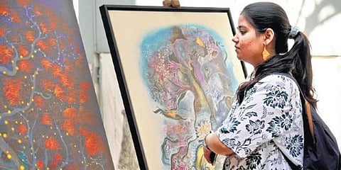 A woman looks at the paintings on the banyan trees of Chevella on the second day of HLF in Hyderabad | Sahithi Sirikonda