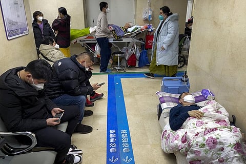 People wearing face masks take a rest as they tend to their elderly relatives rest along a corridor of the emergency ward to provide intravenous drips at a hospital in Beijing. (Photo | AP)