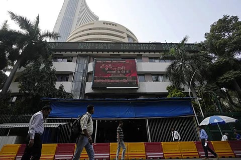 People walk past an electronic display featuring news about Adani Group outside the Bombay Stock Exchange building in Mumbai, India, Friday, Jan. 27, 2023. (Photo | AP)
