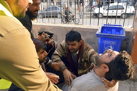 People comfort a man mourning for his family member, who was killed in the suicide bombing inside a mosque, at a hospital, in Peshawar. (Photo | AP)