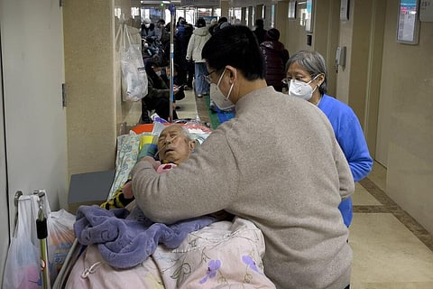 People wearing face masks tend to their elderly relative rest along a corridor of the emergency ward to provide intravenous drips at a hospital in Beijing, Tuesday, Jan. 3, 2023. (Photo | AP)