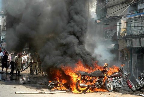 Firefighters extinguish burning motorbikes parked at the AT Road area after a bomb blast in Guwahati on 16 March 2007. (File Photo | AFP)
