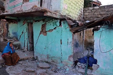A resident sits next to a cracked wall of her house at Joshimath in Chamoli district, Uttarakhand on January 8, 2023. (Photo | AFP)