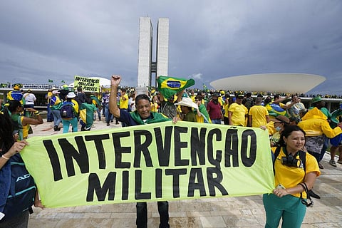 Rioters and supporters of Brazil's Ex-President Jair Bolsonaro, hold a banner that reads in Portuguese 'Military Intervention' as they storm the National Congress building in Brasilia. (Photo | AP)
