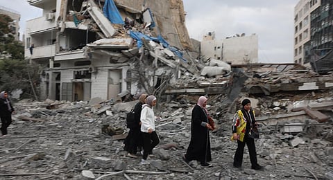 Palestinian women walk through debris amid the destruction from Israeli airstrikes in Gaza City's al-Rimal neighbourhood. (Photo | AFP)