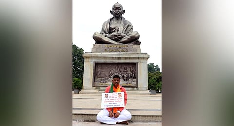 BJP MLA Muniratna demanded the state government for the grants to his constituency which were earlier granted during the BJP government, in front of Gandhi statue at Vidhana Soudha .(Photo | EPS)