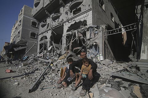 Palestinians sit outside their house following Israeli airstrikes in Rafah refugee camp, southern Gaza Strip, Thursday, Oct. 12, 2023. (Photo | AP)