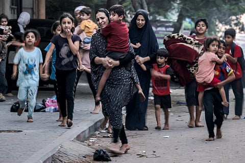 Palestinian women with their children fleeing from their homes following Israeli air strikes rush along a street in Gaza City on October 11, 2023. (Photo | AFP)