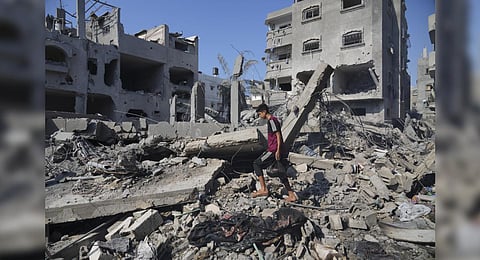 Palestinians stand by the building destroyed in an Israeli airstrike in Deir al-Balah, south of the Gaza Strip | AP