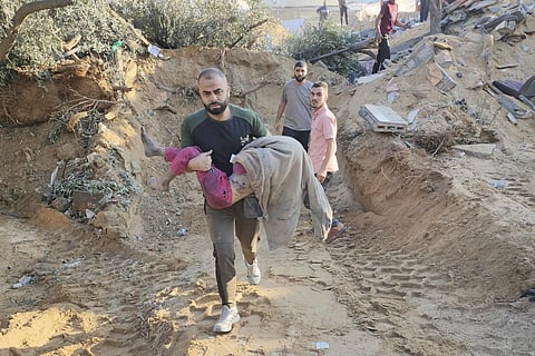 A Palestinian carries a child killed in Israeli airstrikes in Deir el-Balah Gaza Strip, Sunday, Oct 15, 2023.