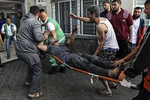 An injured Palestinian man is carried on a stretcher into the al-Shifa Hospital, following Israeli airstrikes on Gaza City. (Photo | AP)