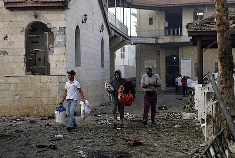 Palestinians carry belongings as they leave al-Ahli hospital, which they were using as a shelter. (Photo | AP)