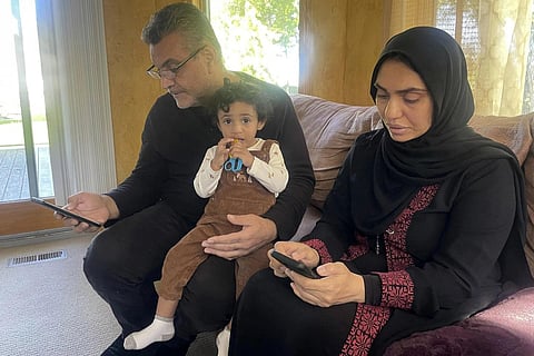 Fatma Abumousa and Jehad Adwan check their phones for information about Abumousa's killed and injured relatives as their nearly 2-year-old son Yaman looks on, Oct 16, 2023 (Photo | AP)