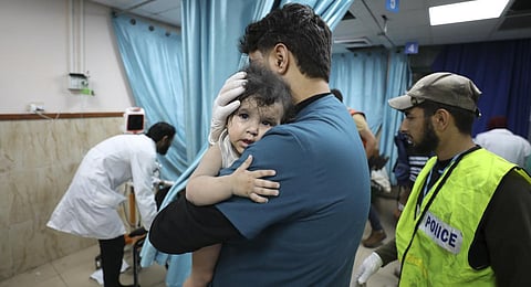 Palestinian medic holds a child wounded in Israeli air strike on the Gaza Strip, in Deir el-Balah, Sunday, Oct. 22, 2023. (Photo | AP)