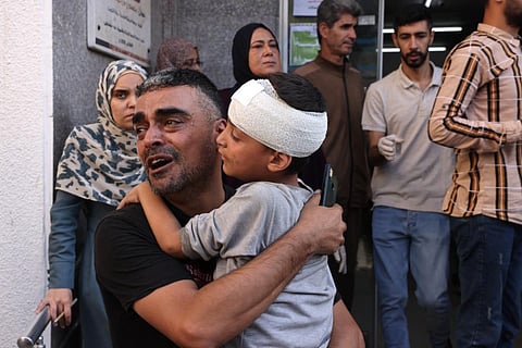 A Palestinian man carries a boy after he was treated for a head injury at the hospital, following an Israeli air strike in Rafah, in the southern Gaza Strip. (Photo | AFP)