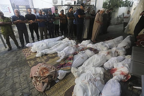 Palestinians pray by the bodies of people killed in the Israeli bombardment of the Gaza Strip in Rafah, Wednesday, Oct 25, 2023. (Photo | AP)