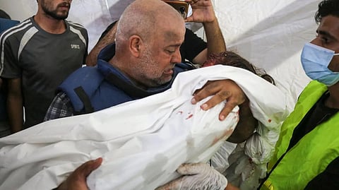 Wael Dahdouh mourns over the body of his seven-year-old daughter, who was killed along with his wife and son in an Israeli air raid in the Nuseirat refugee camp. (AFP)