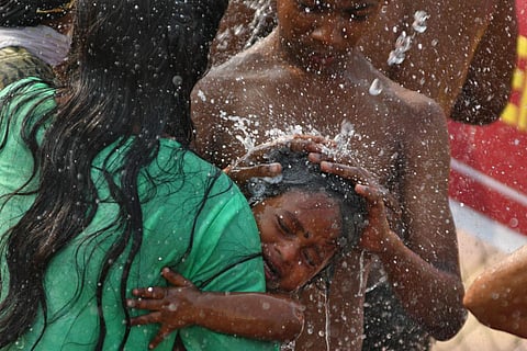 A girl cries even as her mother gives her a shower before taking her for a darshan of the Goddess in Vijayawada on Saturday. (Photo| Prasant Madugula)