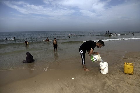 Palestinians resort to the seawater to bathe and clean their tools and clothes due to the continuing water shortage in the Gaza Strip, on the beach of Deir al-Balah, Oct. 29, 2023. (Photo | AP)