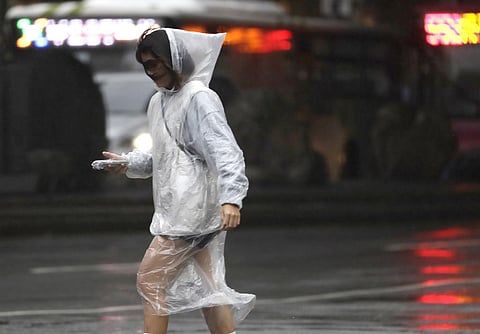 A woman walks in the rain as Typhoon Koinu approaches to Taiwan in Taipei. (Photo | AP)