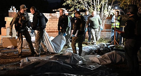 Ukrainian policemen carry the body of a victim who died in a Russian strike that destroyed a shop and a cafe in the village of Groza on October 5, 2023. (Photo | AFP)