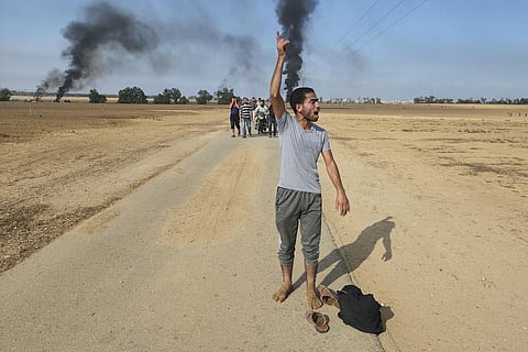 Palestinians walk away from the kibbutz of Kfar Azza, Israel, near the fence with the Gaza strip on Saturday, Oct. 7, 2023.