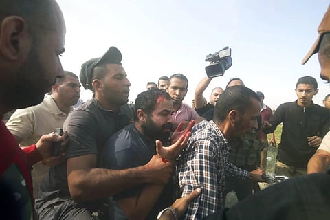 Palestinians transport a captured Israeli civilian, center, from Kibbutz Kfar Azza into the Gaza Strip on Saturday, October 7, 2023. (AP)