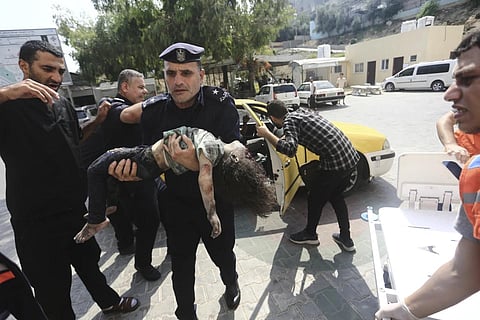 Hamas police officer carries a wounded girl into a hospital in Beit Lahiya, Gaza Strip, Oct 8, 2023. (Photo | AP)