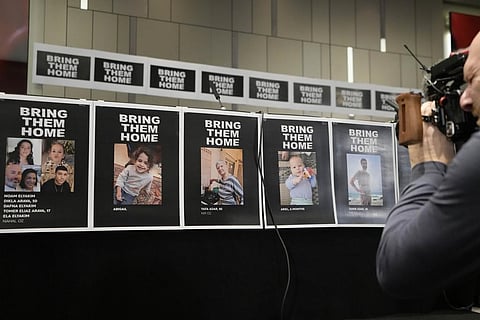 FILE: A cameraman films posters with photos of missing persons ahead of a press conference by family members of Israeli hostages at a hotel in London, Oct. 12, 2023. (Photo | AP)