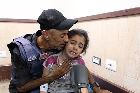 A Palestinian journalist comfort his niece wounded in an Israeli strike on her family home in Nusseirat refugee camp, in a hospital in Deir el-Balah, Gaza Strip, on Oct. 22, 2023. (AP)