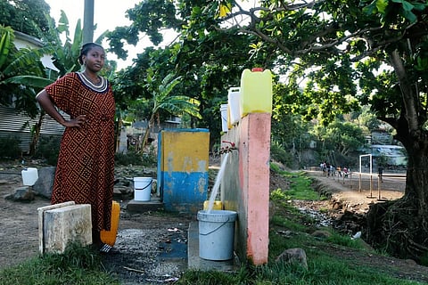 A woman waits for her bucket to be full at a water point in M'tsamoudou, near Bandrele, on the French Indian Ocean territory of Mayotte. (File Photo | AP)