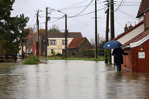 A woman walks in a flooded street in Le Doulac near Saint-Omer, northern France on November 14, 2023. (Photo | AFP)