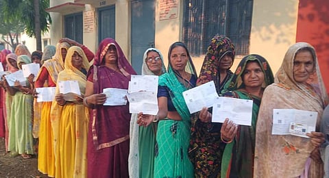 Voters show their identification cards as they wait in a queue at a polling station to cast their votes for the Madhya Pradesh. (Photo |PTI)