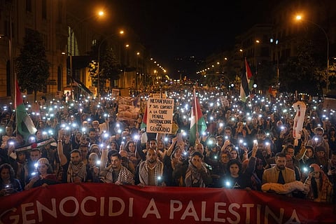 Demonstrators use the flashlights on their mobile phones as they protest against Israeli attacks on Gaza, in Barcelona, Spain on Nov 11, 2023. (Photo | AP)